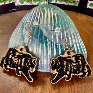 meemers-earrings Pair of red oak Meemers dangle earrings with black engraved cat designs on an iridescent teal stand